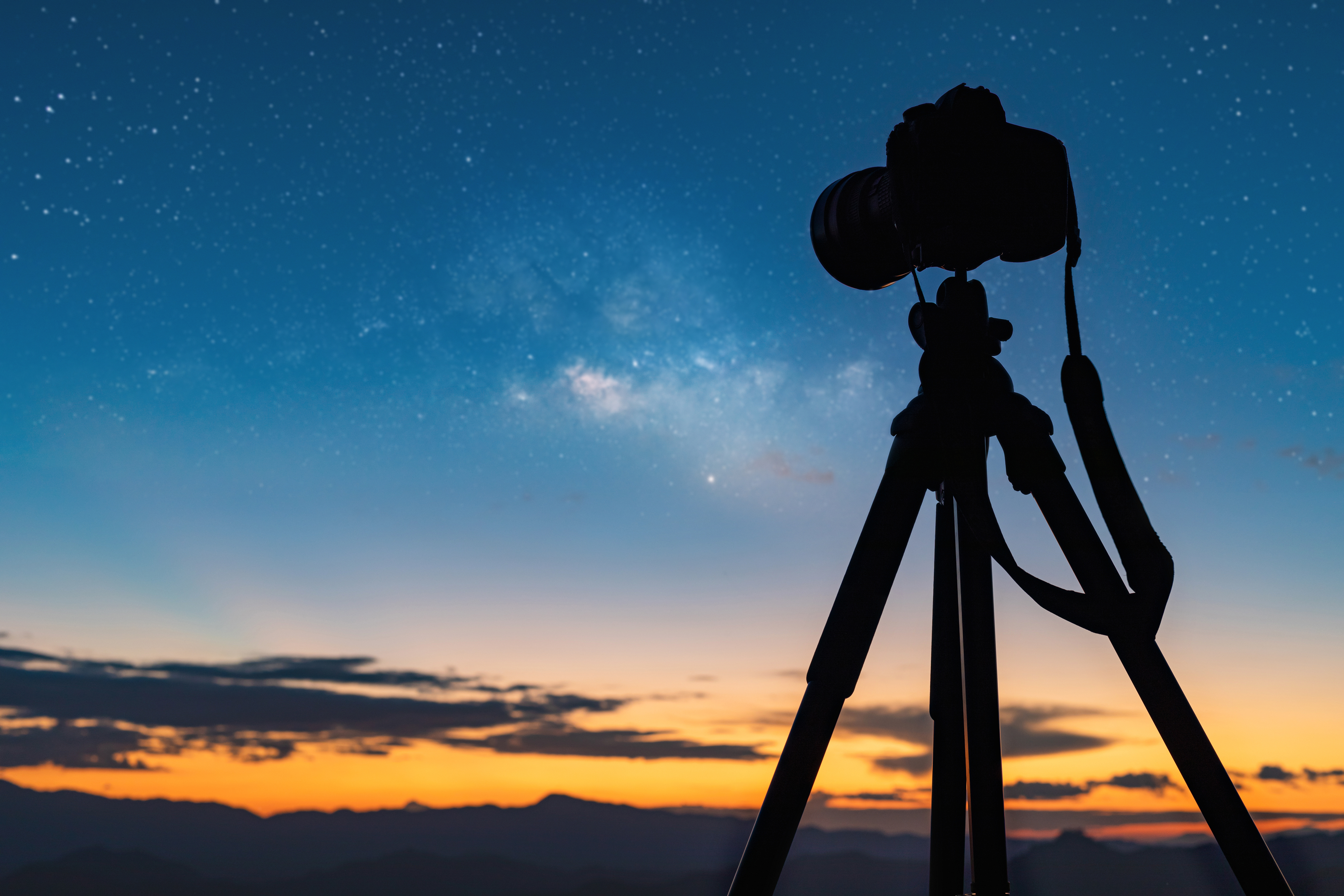 A DSLR on a tripod in front of a sunset