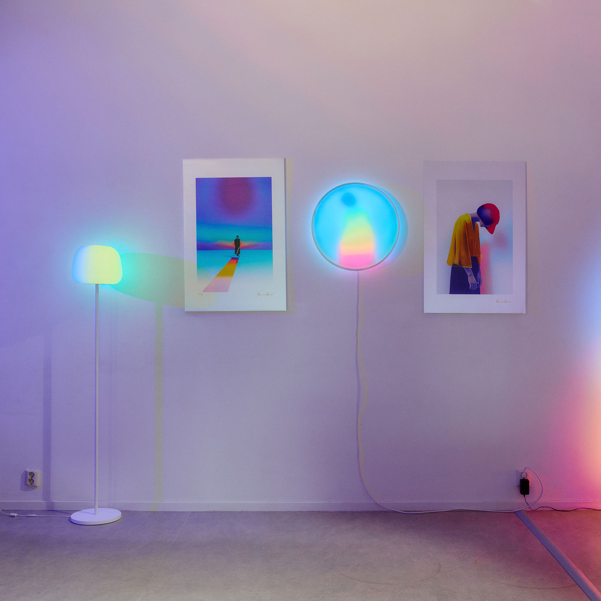 Multicoloured smart wall, standing and ceiling lights in white room with portrait photography on walls