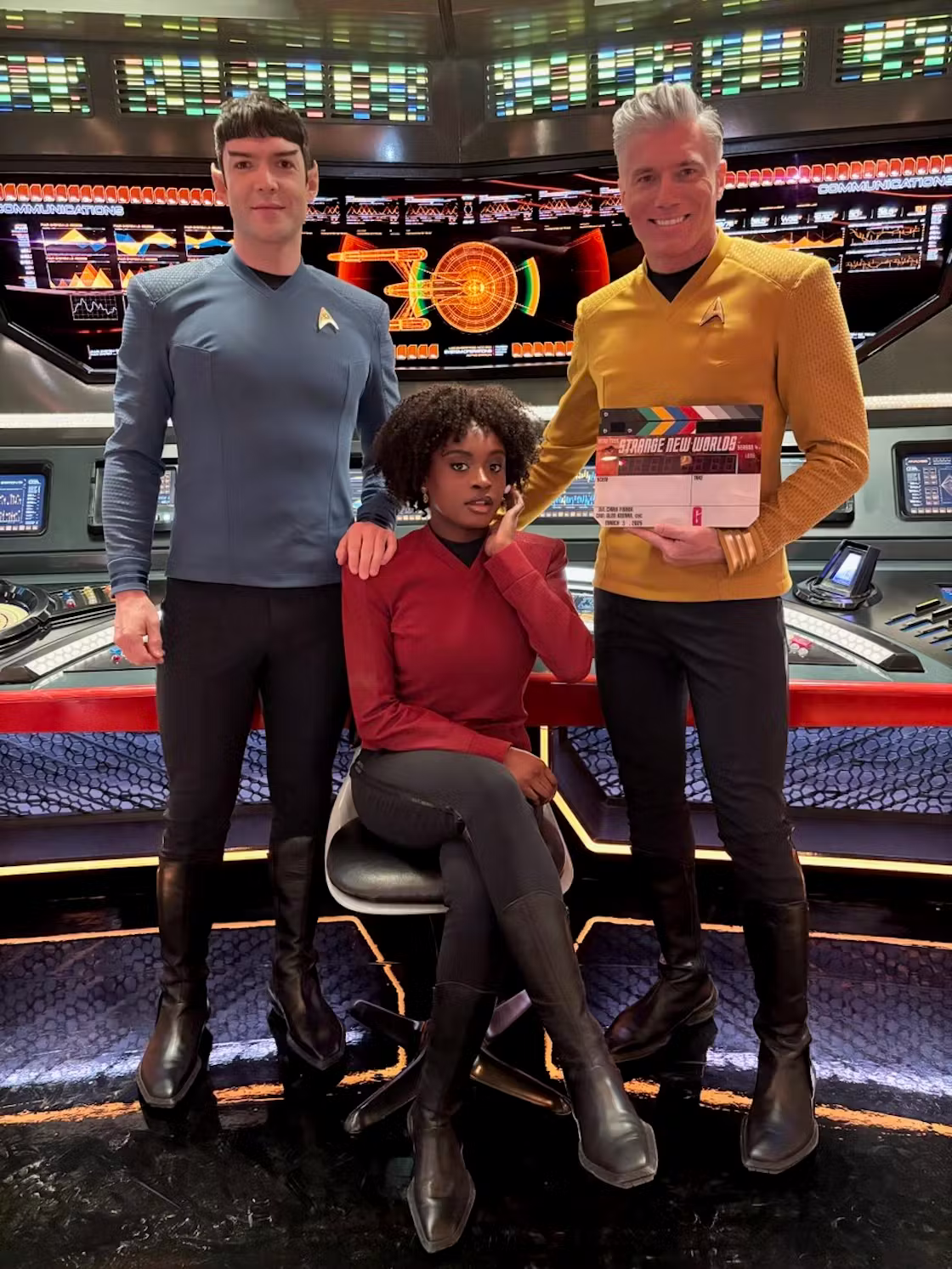 Three sci-fi characters pose on a starship bridge set