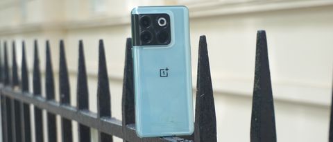 En ljusblå OnePlus 10T står lutad mot toppen av ett staket med baksidan vänd mot kameran.
