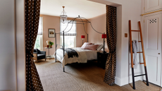 a bedroom with with polka dot drapes acting as a partition between the sleeping area and