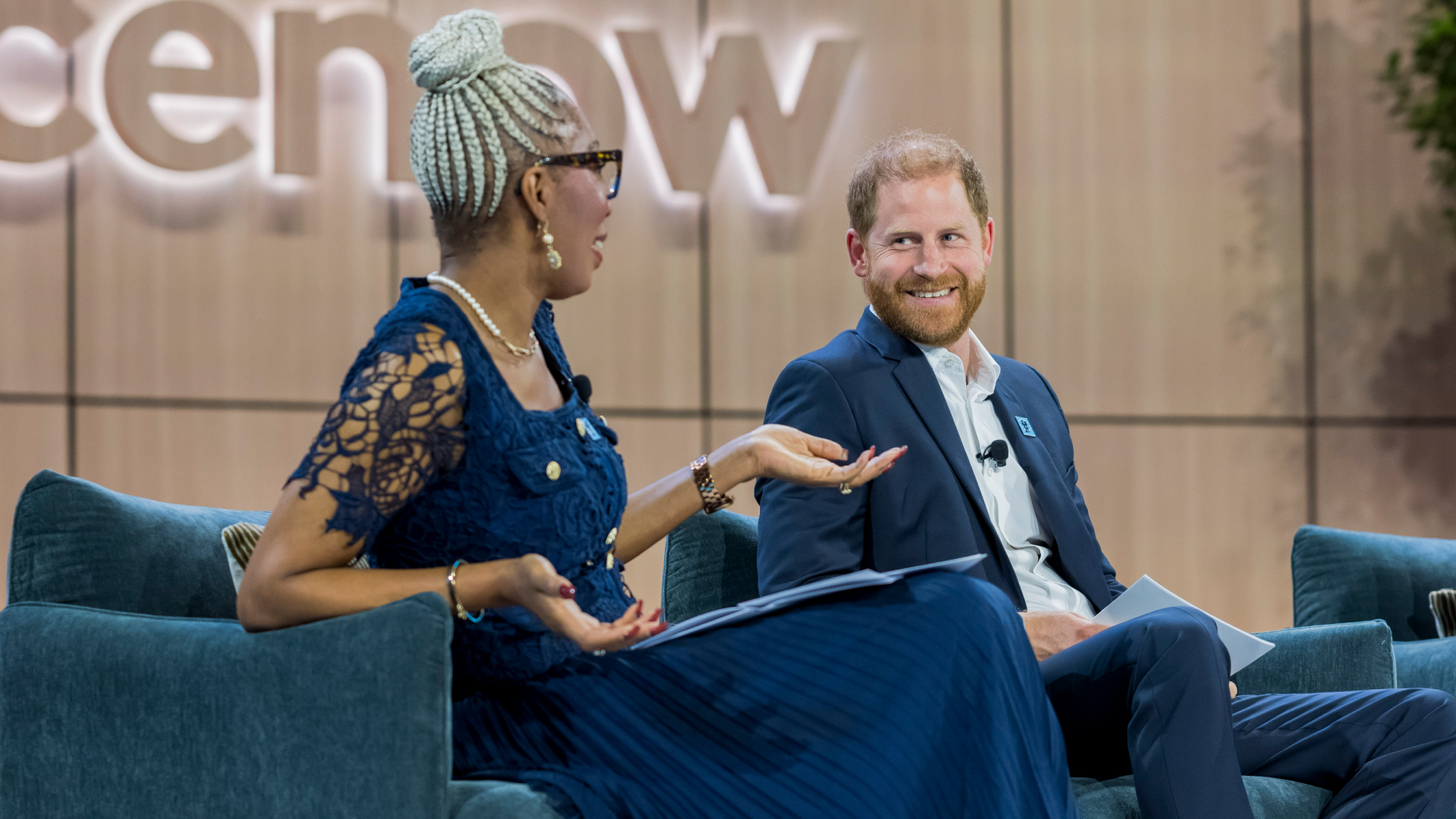 Prince Harry talking to Tessy Ojo of the Diana Award on a blue sofa