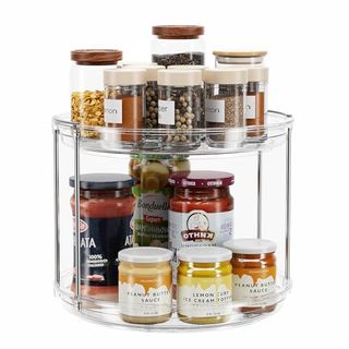 2 Tier Lazy Susan Turntable Organizer 9.25'' with clear plastic sides and stainless steel ride separating the two tiers. Loaded with jars of condiments on the taller lower space and herbs on the top shelf