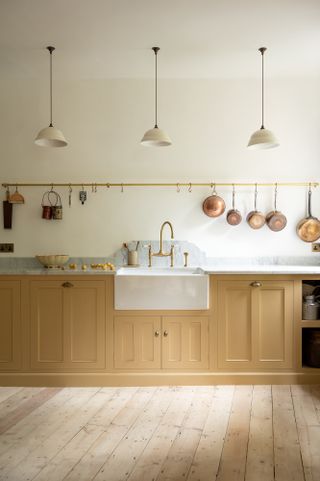 A kitchen with a utensil rail above the sink displaying copper pans