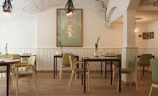 Restaurant with a neutral interior, huge print on the wall as a center piece, complete with brick ceilings in white.