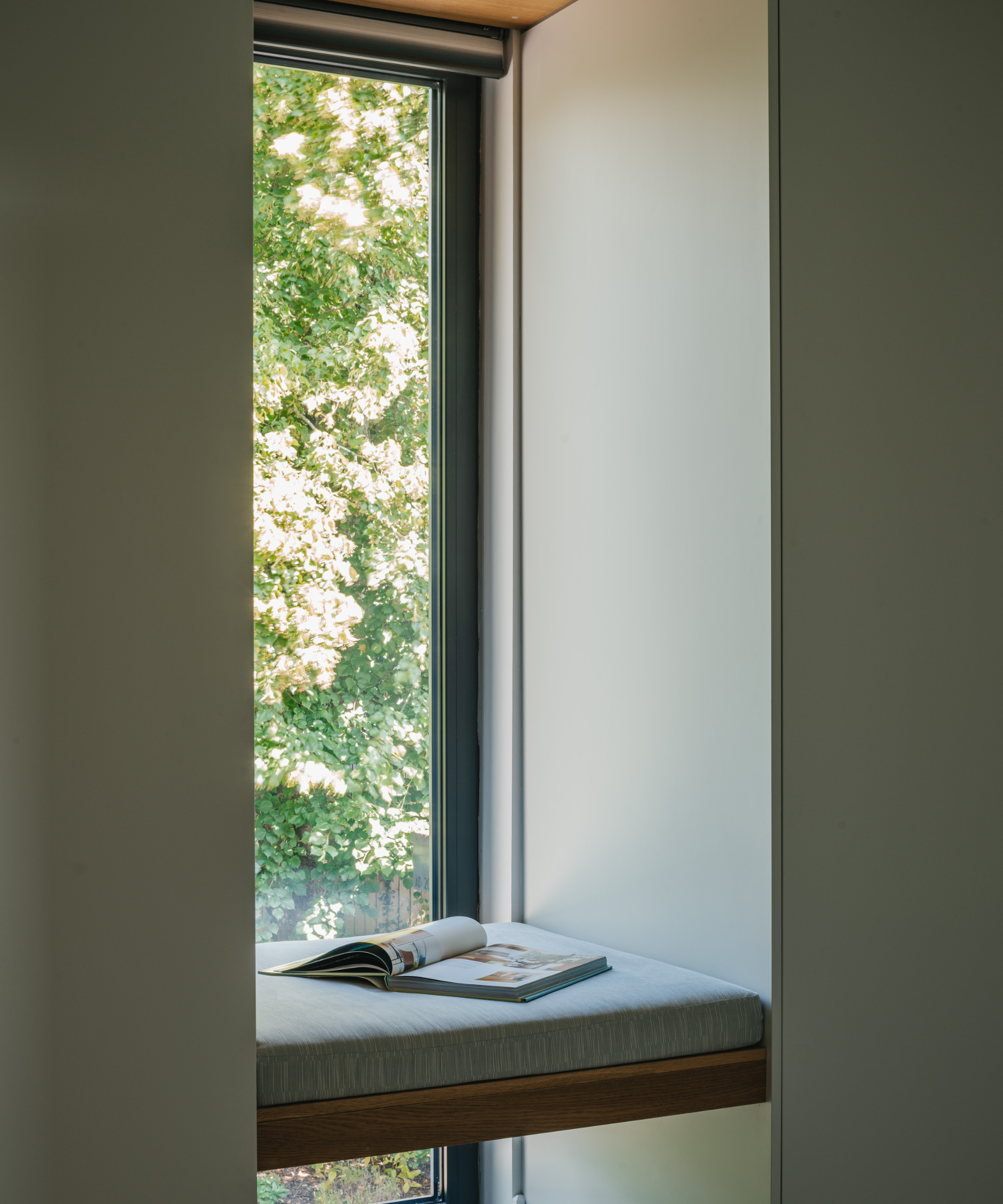 Window seat opposite vertical window with a magazine rested on the seat