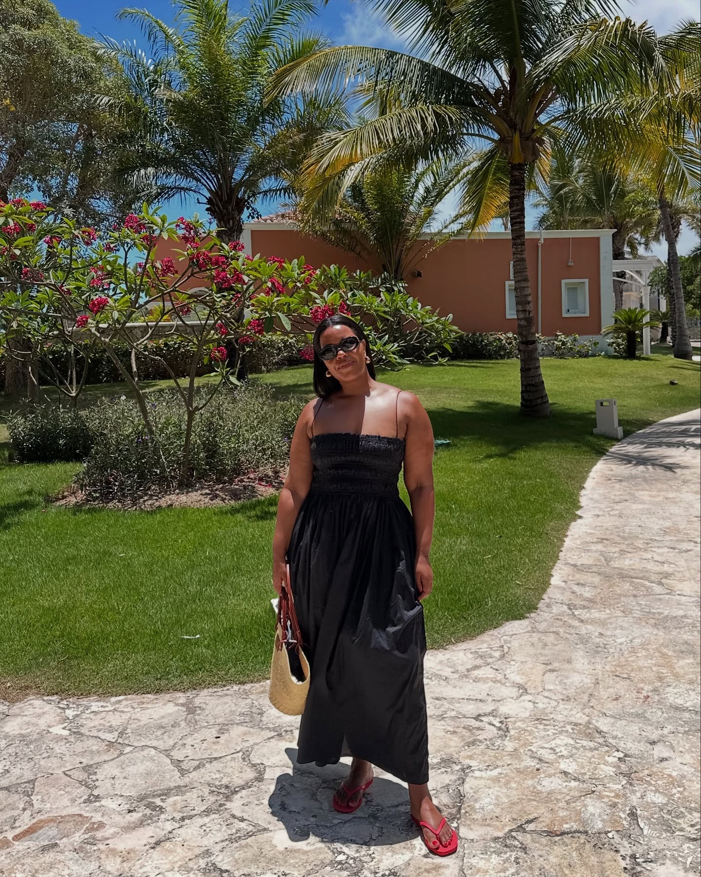 The woman is wearing a ruched dress and red sandals.
