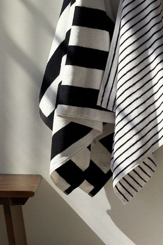 two striped towels hanging on the wall next to a stool