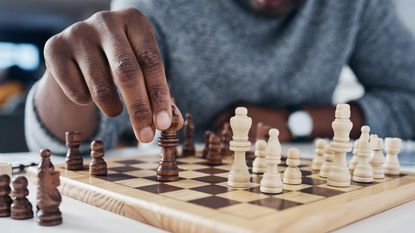 A man moves a piece on a chess board.