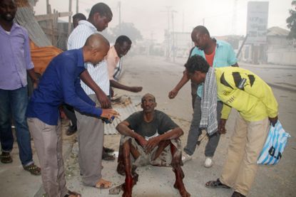 Somalians assist a civilian injured in a terrorist attack on a Mogadishu hotel
