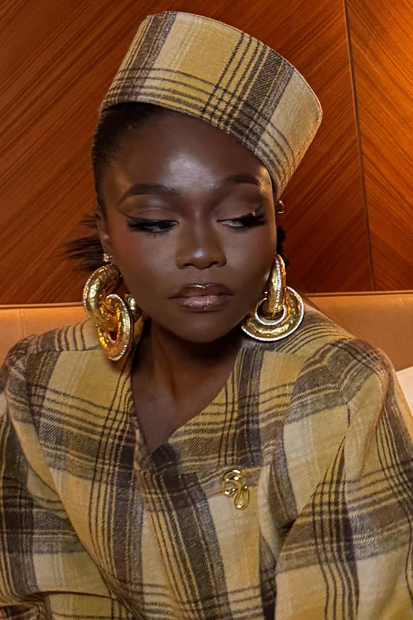 a woman wearing gold statement earrsings