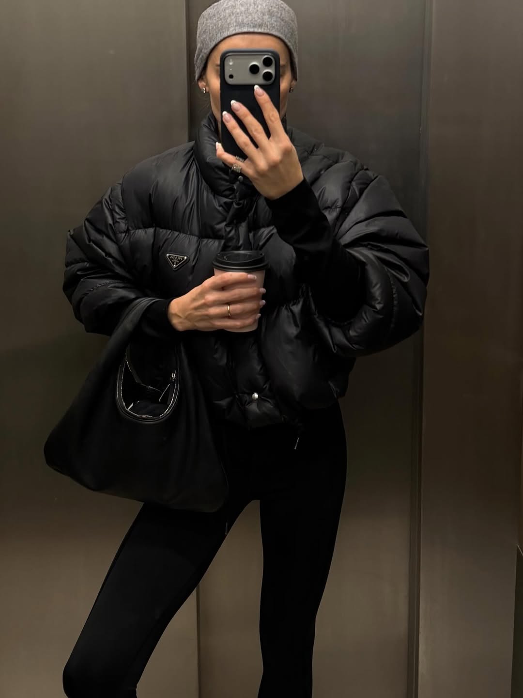 @rikkekrefting wears black leggings, black puffer coat, black suede bag