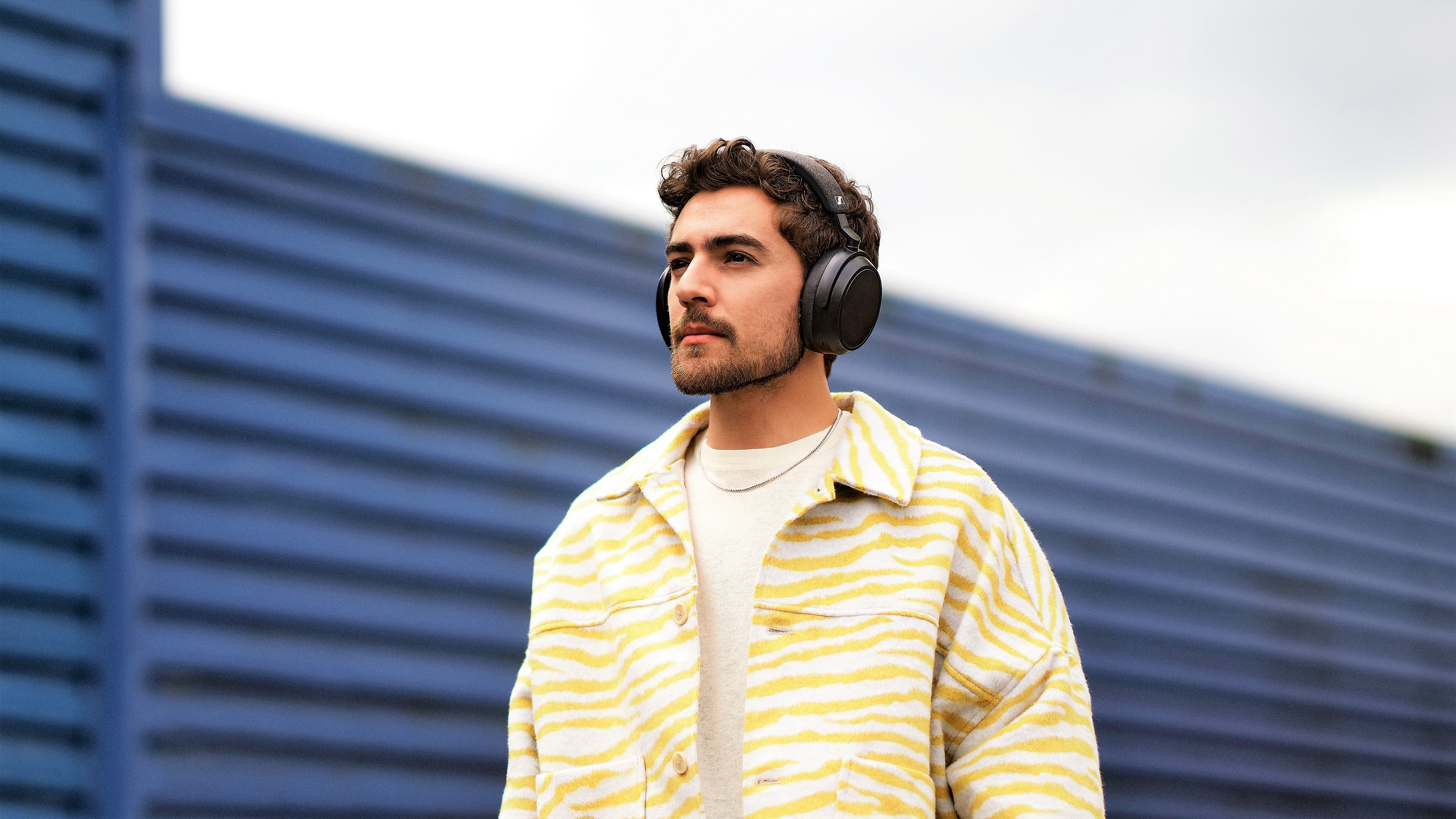Sennheiser PR shot of man wearing Momentum 4 Wireless headphones outdoors