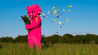 Pink bear with flower petals blowing in the wind