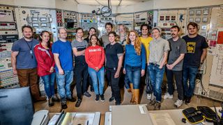 A group of researchers pose for a photo in a control room