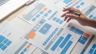 person working on printouts of website design on desk