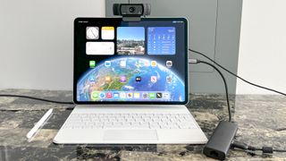 external USB webcam attached to the top of an iPad Air with Magic Keyboard showing home screen