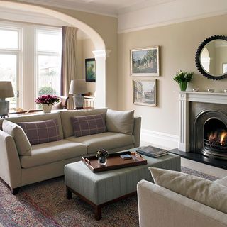sitting room in edwardian home with sofa and round wall hanging mirror above fireplace