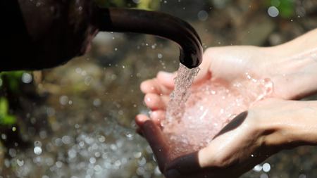 Hands of woman under fresh water spring, focus on water, in Borjomi