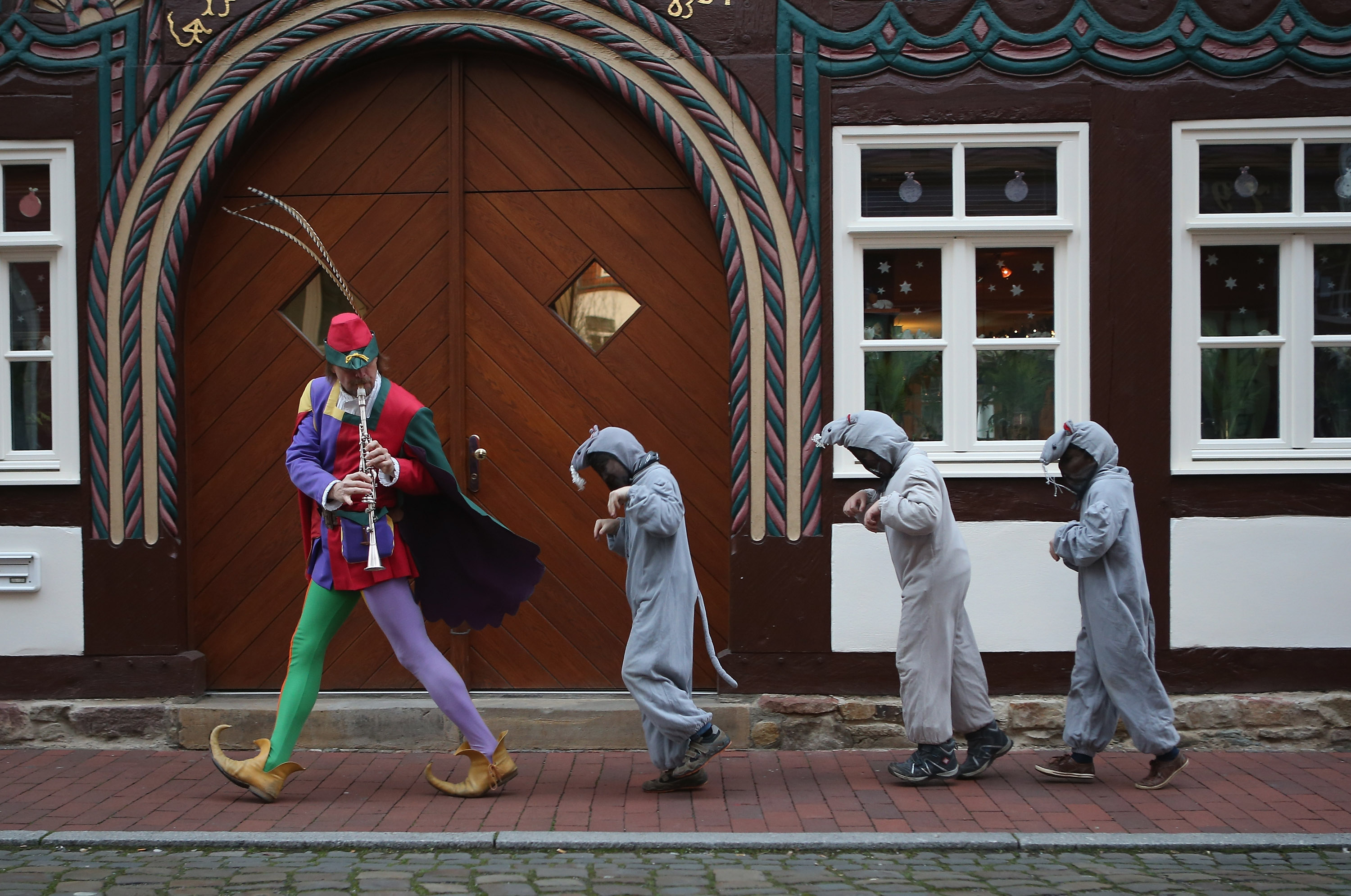 A man dressed as the Pied Piper leads three children dressed as rats through the streets of Hamelin, Germany