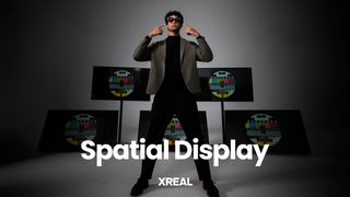A person points at the Xreal Air glasses they're wearing, multiple displays are behind them, the words "Spatial Display" are in front of them