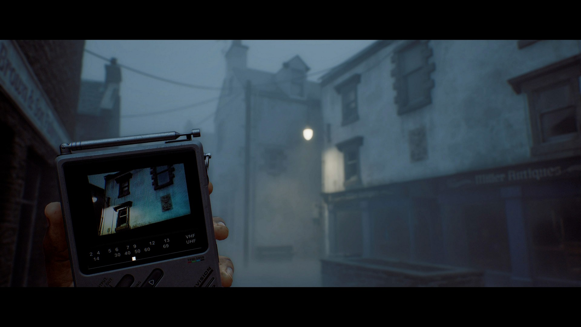 Simon walks through a foggy town street in Silent Hill Townfall scanning surroundings with a handheld CRTV