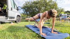 A young woman exercising outdoors using a resistance band and a yoga mat 