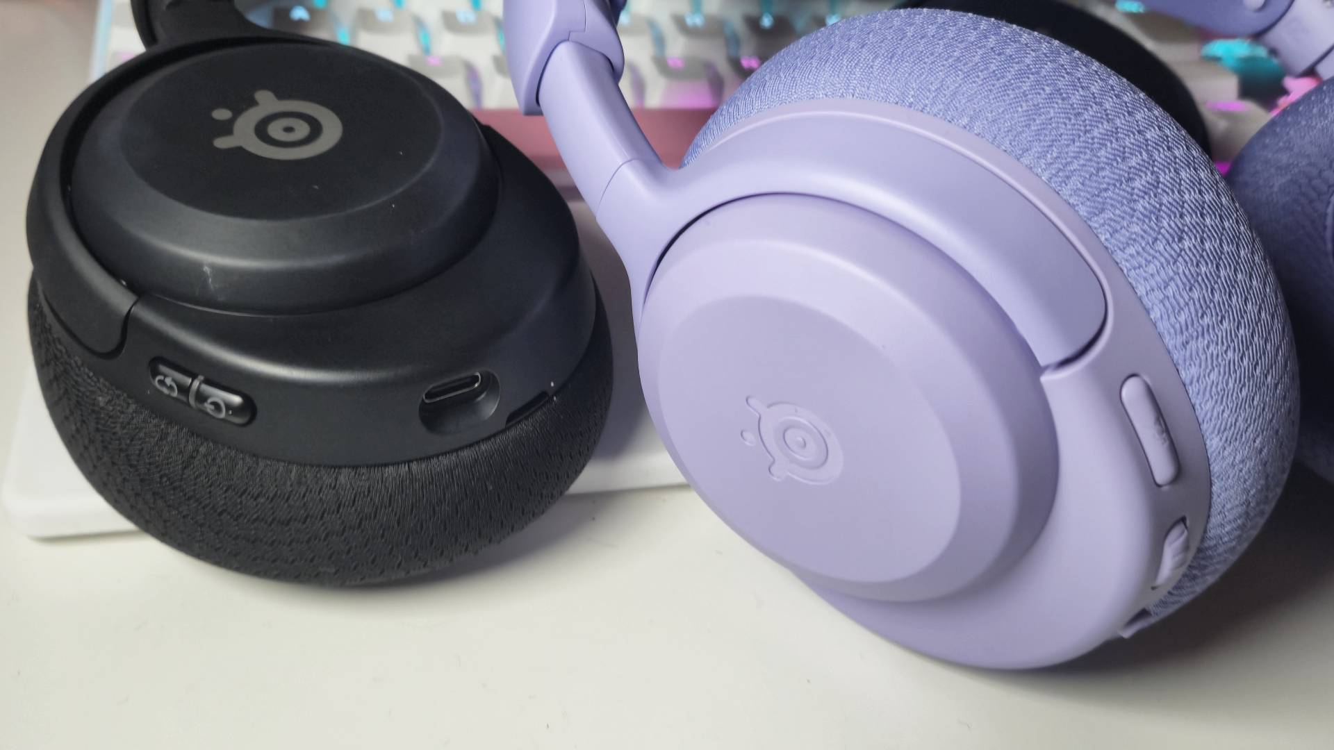 Photo by Rosalie Newcombe of the Arctis Nova 5 sitting next to the Arctis Nova 3 Wireless headset.