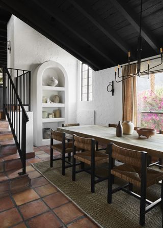 mediterranean style dining room designed by bobby berk with white walls and solid wood dining table