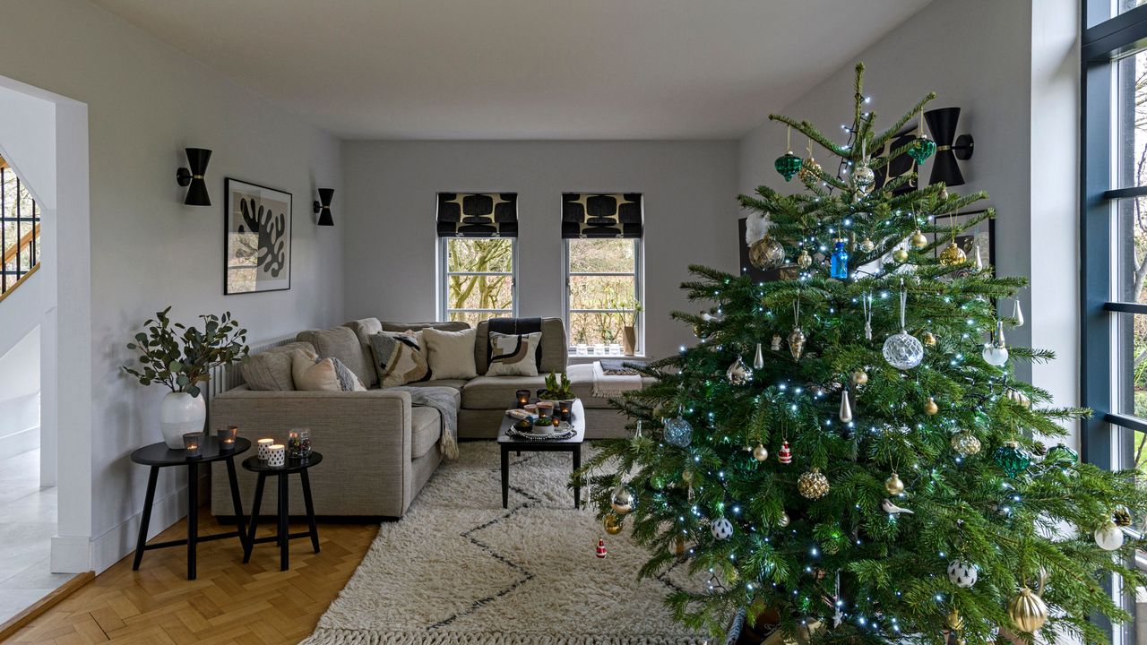 Large Christmas tree decorated with blue ornaments and fairy lights in living room