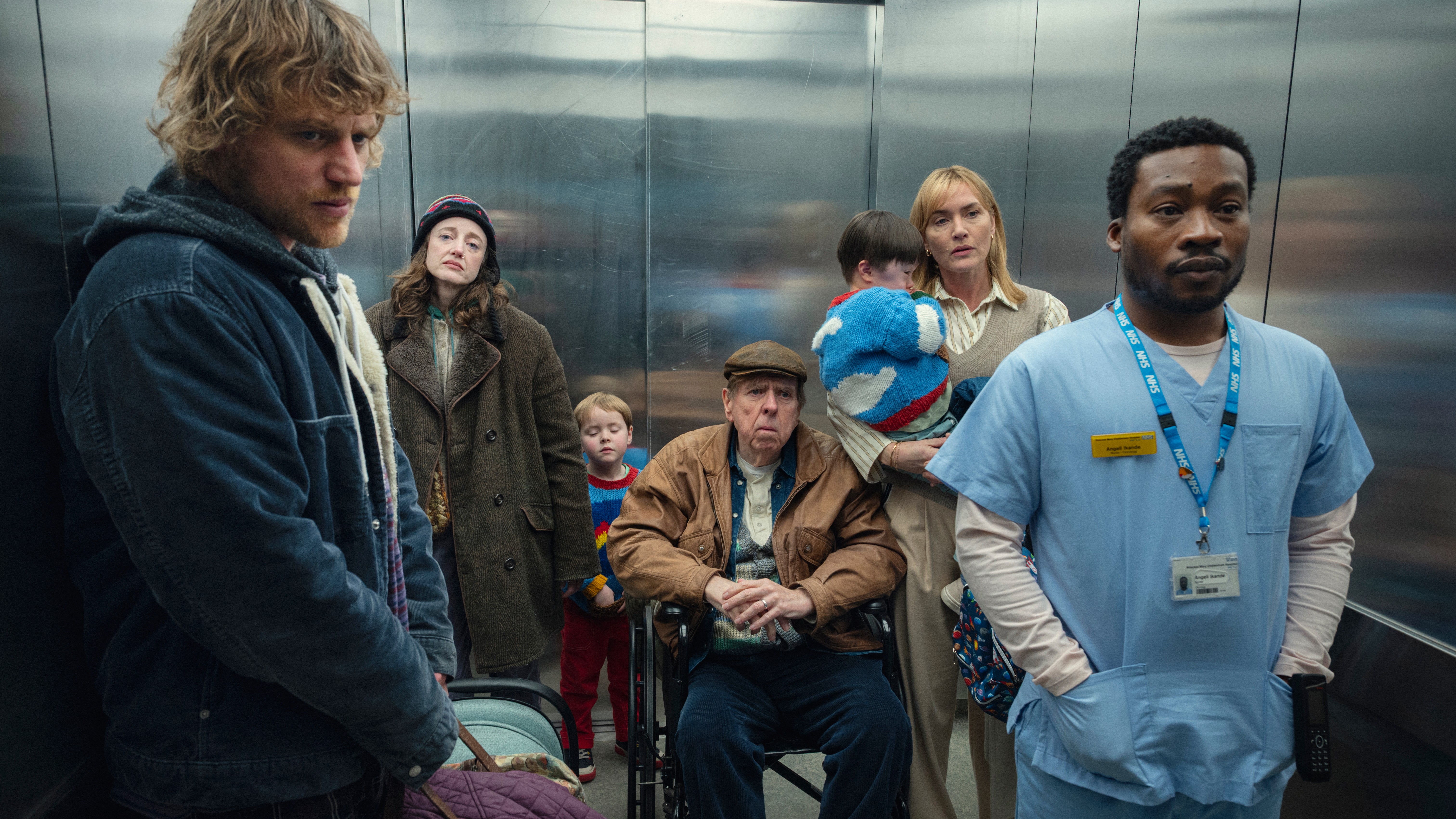 L-R: Connor (Johnny Flynn), Molly (Andrea Riseborough), Bernie (Timothy Spall), Julia (Kate Winslet) and Angel (Fisayo Akinade) in an hospital elevator in a scene from Netflix's &amp;quot;Goodbye June&amp;quot;