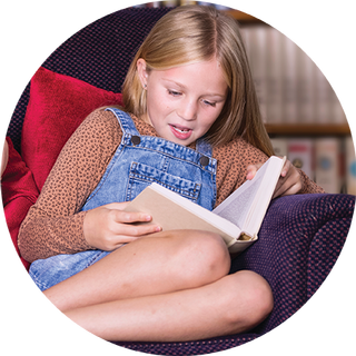 Image of young girl sitting on a chair reading a book