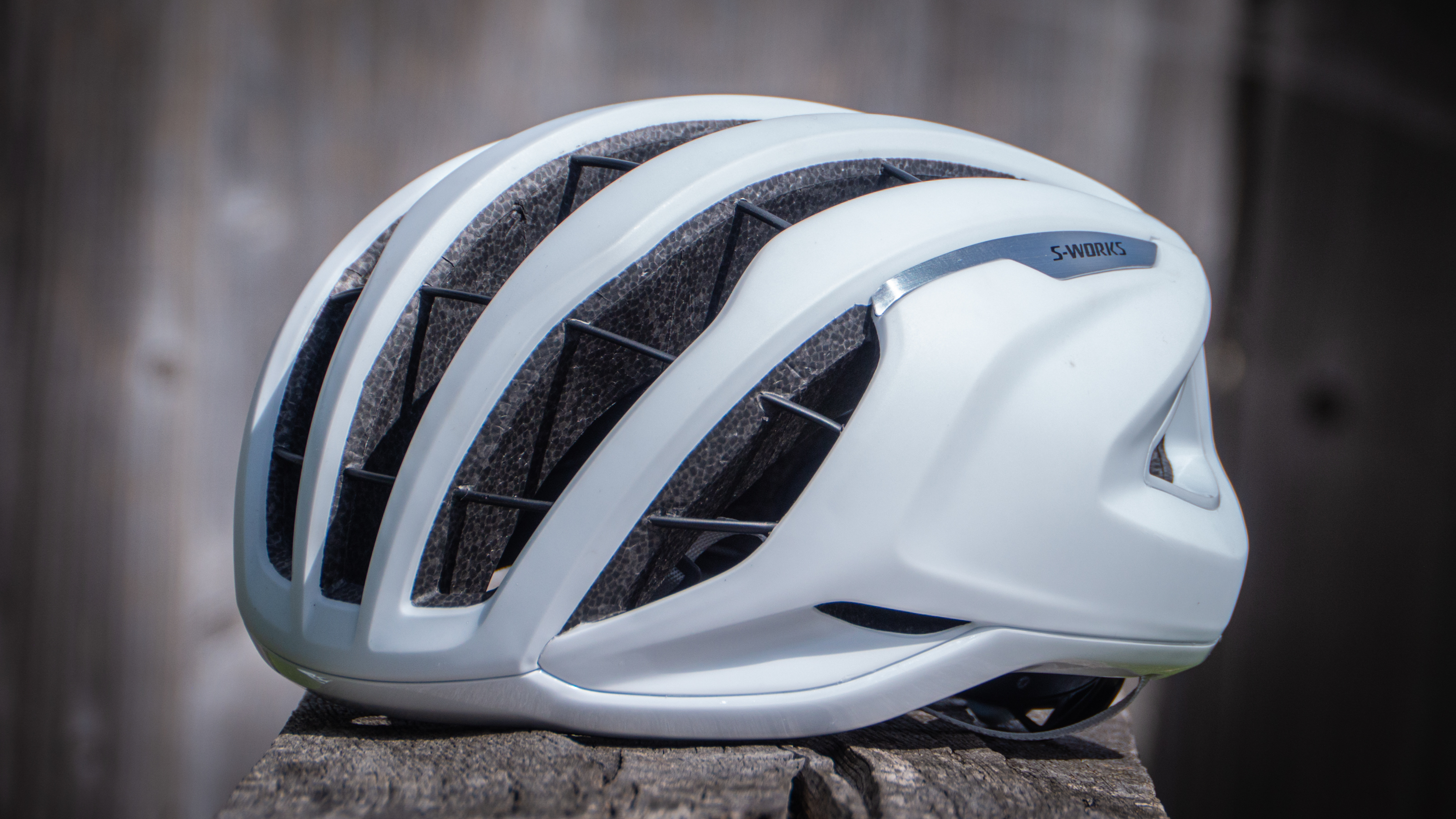 An front-angle view of a white Specialized Prevail 3 helmet sitting on a wooden bench