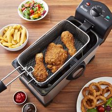 Swan deep fryer containing fried chicken on wooden surface