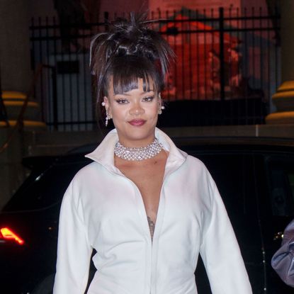 Rihanna wearing a white shirty, diamond chocker, and an updo hairstyle. 