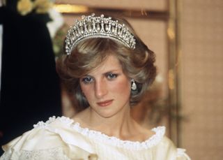 Diana, Princess of Wales, wearing a cream satin dress by Gina Fratini with the Queen Mary Cambridge Lover's Knot Tiara and diamond earrings attends a banquet on April 29, 1983 in Auckland, New Zealand