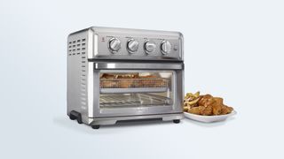 Cuisinart Air Fryer Toaster Oven cooking food inside with a tray of fries and fried chicken beside it