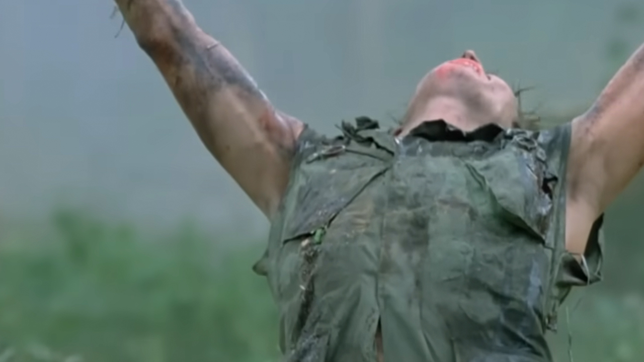 Willem Dafoe with his arms up in the air as he dies in Platoon