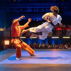 Xolo Maridueña as Miguel Diaz (right), hitting an opponent with a flying kick, in 'Cobra Kai.'