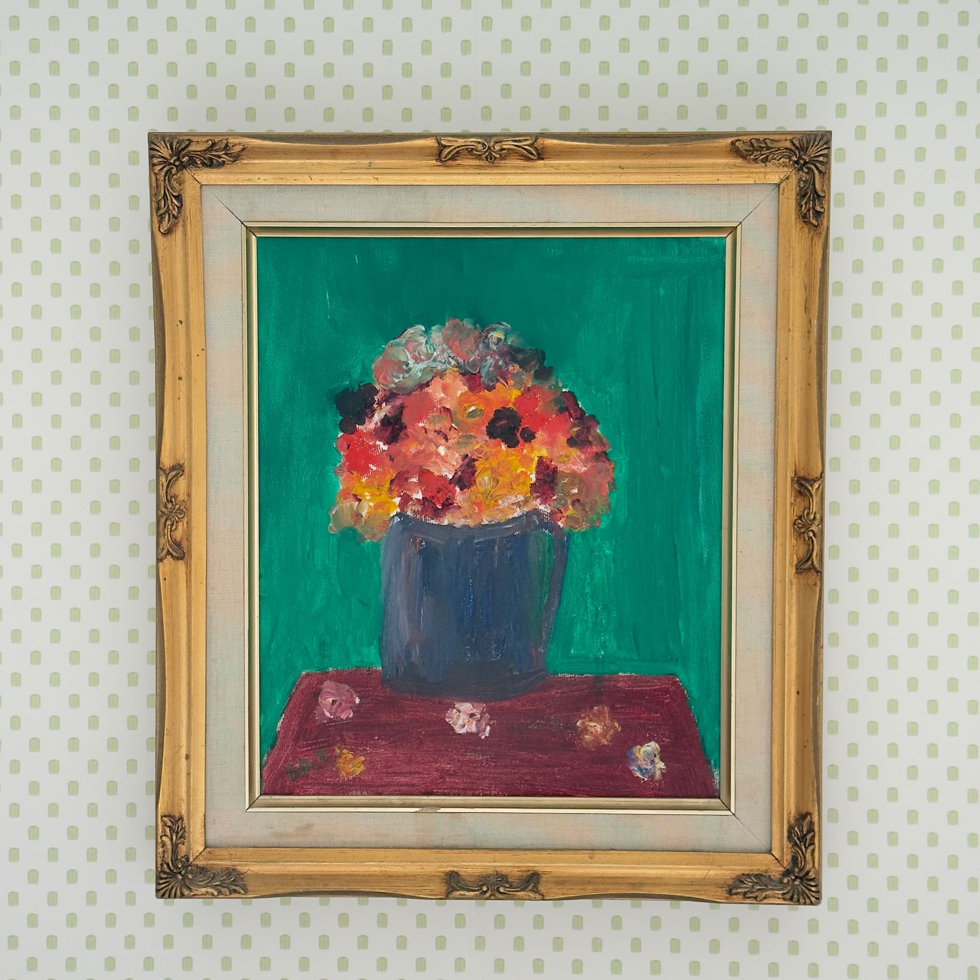 Painting of flowers in gold frame on wall with green polka dot wallpaper