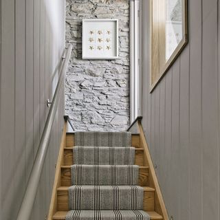 A grey hallway with wooden staircase and grey handrail