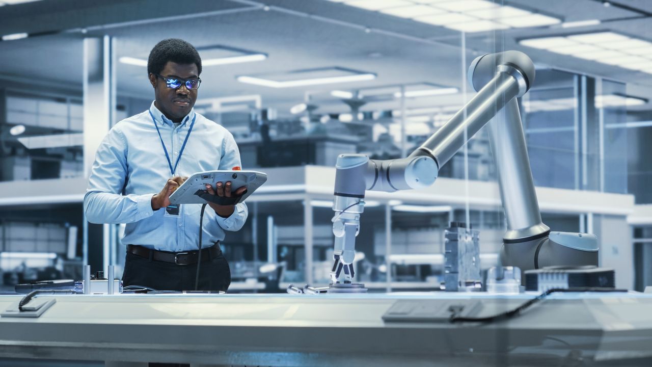 A man uses a tablet to control an AI robot.