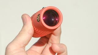 Nocs Zero Tube rugged monocular in orange shown close-up in a user's hand
