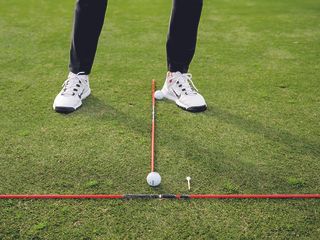 Gary Munro demonstrating a ball striking drill using alignment sticks and a tee