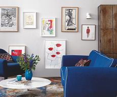 white living room with blue sofa decorated with simple things like art and vases