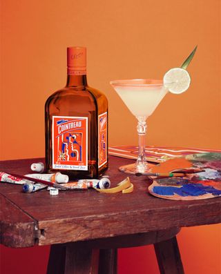 Cointreau bottle sits on a wooden table with a orange backdrop.