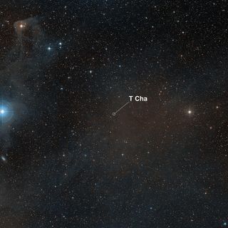 This visible-light wide-field image of the region around the young star T Cha was created from photographs taken through red and blue filters and forming part of the Digitized Sky Survey 2. The star appears close to the centre. Some of the dust associated with this star-forming region is faintly visible in the background, particularly at the upper left.