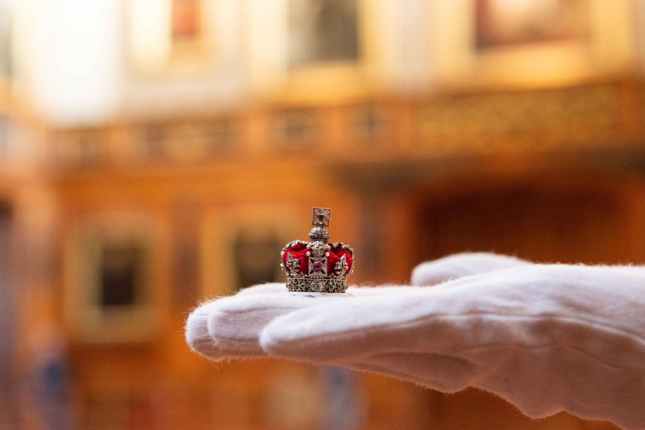 A tiny crown from Queen Mary&#039;s Dolls&#039; House, held up for inspection by curator Kathryn Jones.