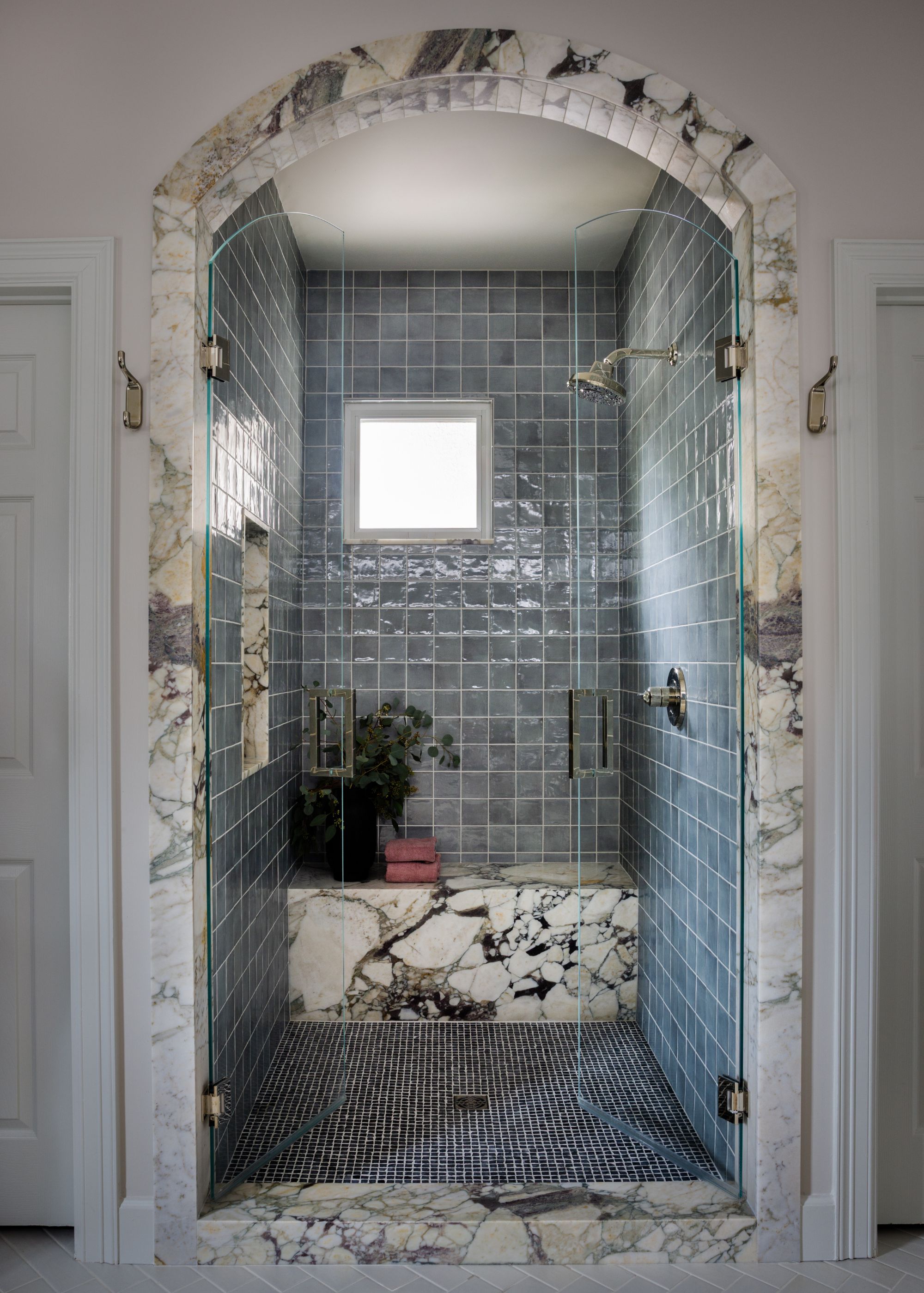 A bold powder room featuring dark floral wallpaper with pineapple motifs. A scalloped gold mirror hangs above a marble-topped vanity with a dark purple base and brass fixtures.