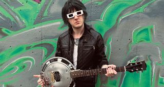 The Frst’s Mikei Gray in white sunglasses with his DIY hubcap guitar